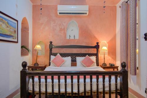 a bedroom with a bed with two lamps on tables at Fort Dadhikar, Alwar in Alwar