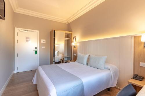 a hotel room with a white bed and a mirror at Hotel Artaza in Getxo