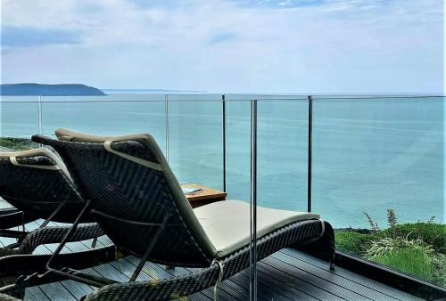 a wicker chair and table on a balcony with the ocean at Watersmeet Hotel in Woolacombe