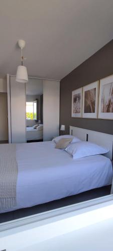 une chambre avec un grand lit blanc et un miroir dans l'établissement La maison de Goudargues, à Goudargues