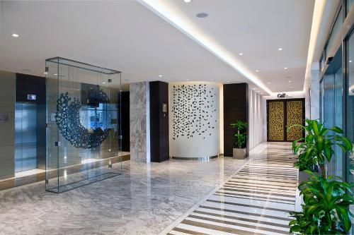 un hall d'un immeuble avec un couloir orné de plantes dans l'établissement Grayton Hotel by Blazon Hotels, à Dubaï