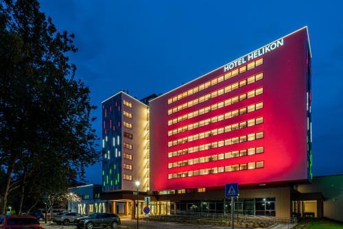 un gran edificio con una señal roja delante de él en Hotel Helikon, Keszthely en Keszthely