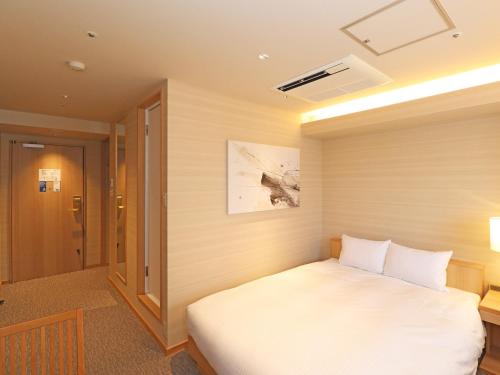 um quarto com uma cama branca num quarto em Chisun Inn Yokohama Tsuzuki em Yokohama