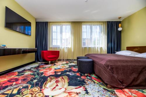 um quarto de hotel com uma cama e uma cadeira vermelha em Amsterdam Plaza Hotel & SPA em Palanga