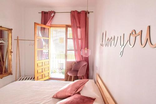 a bedroom with a bed and a chair and a window at Meraki: tu hogar en Frigiliana in Frigiliana