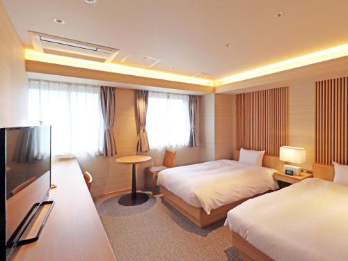 a hotel room with two beds and a flat screen tv at Chisun Inn Yokohama Tsuzuki in Yokohama