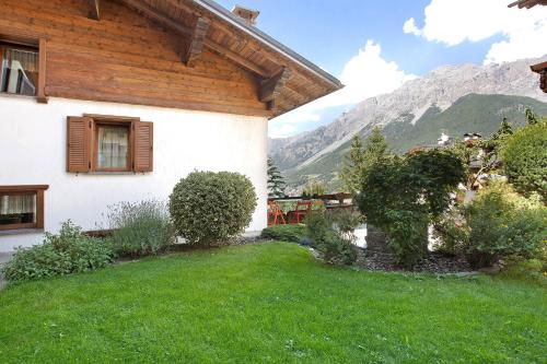 a house with a green yard in front of a mountain at Aria di Casa Reit in Valdisotto