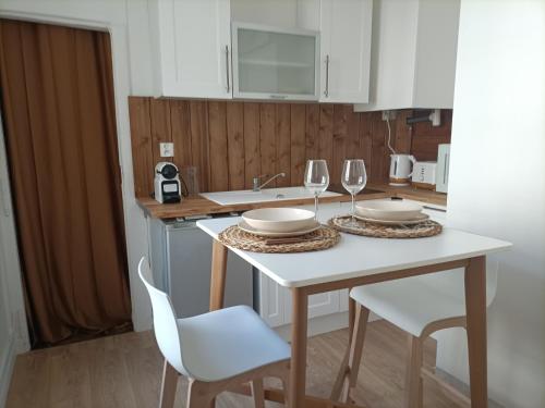 une cuisine avec une table blanche avec deux chaises et des verres à vin dans l'établissement Studio chaleureux - Centre ville de Caen, à Caen
