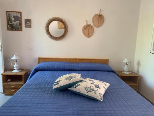 - un lit bleu avec un oreiller et un miroir mural dans l'établissement Flaviana Salento Holiday House, à Pulsano