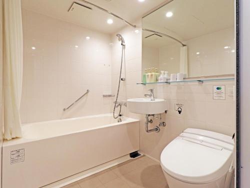 a bathroom with a toilet and a tub and a sink at Chisun Inn Yokohama Tsuzuki in Yokohama