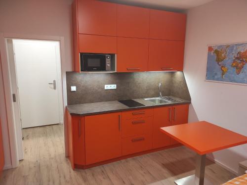 a kitchen with orange cabinets and a sink and a table at Penzion Školička in Prague