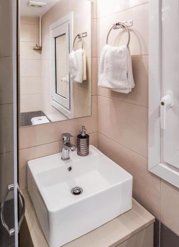 a bathroom with a white sink and a mirror at Byronico Acropolis Apartment by MPS in Athens