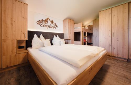 a bedroom with a large white bed with wooden cabinets at Familienbauernhof Samerhof in Pfarrwerfen