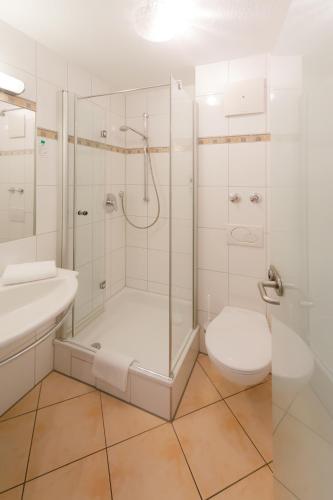 a white bathroom with a shower and a toilet at Hotel-Restaurant Bierhäusle in Freiburg im Breisgau