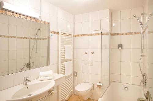 een witte badkamer met een douche, een toilet en een wastafel bij Hotel-Restaurant Bierhäusle in Freiburg im Breisgau