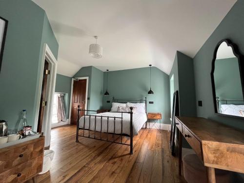 セント・クリアーズにあるピクトン ハウスの緑の壁のベッドルーム1室、鏡付きのベッド1台が備わります。