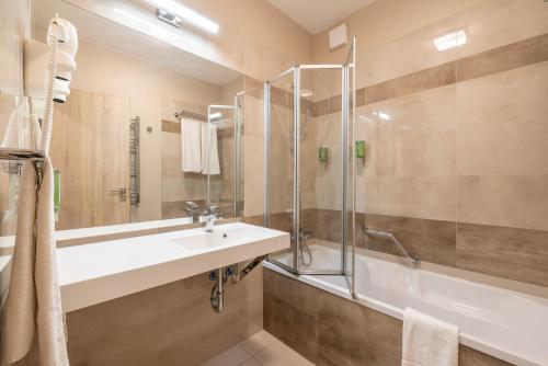 a bathroom with a sink and a shower and a tub at Silver Crown Hotel & Residence, Palace Quarter in Budapest