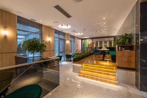 a hotel lobby with yellow stairs and plants at Silver Crown Hotel & Residence, Palace Quarter in Budapest