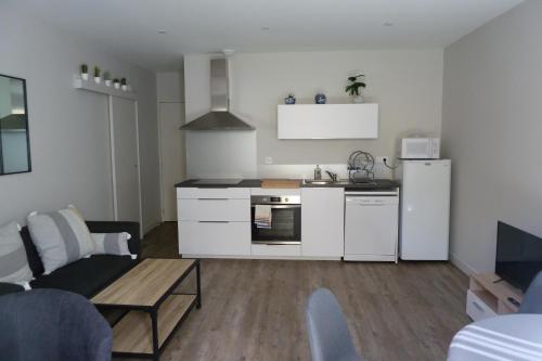 een keuken met witte apparatuur en een woonkamer bij Chez Berni in Millau