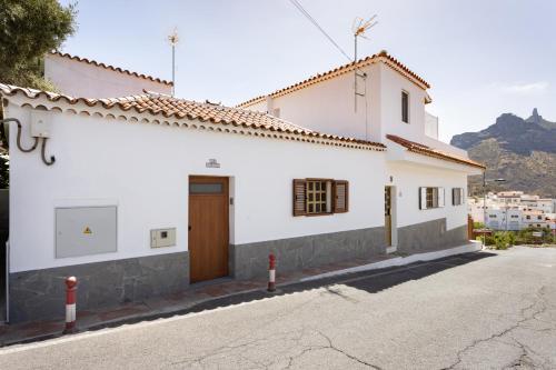 a white building with a brown door on a street at Casa Evaristo with Roque Nublo view in Tejeda
