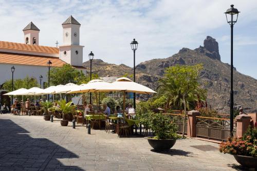 a patio with tables and umbrellas in front of a mountain at Casa Evaristo with Roque Nublo view in Tejeda