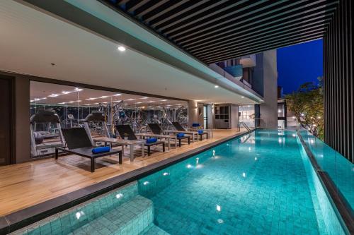 uma piscina interior com cadeiras e uma casa em Aster Hotel and Residence by At Mind em Pattaya Central