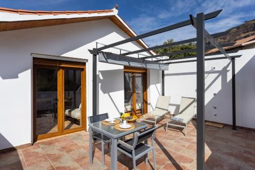 a pergola on a patio with a table and chairs at Casa Maria with Roque Nublo view in Tejeda