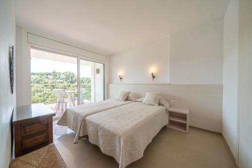 een witte slaapkamer met een bed en een balkon bij Apartamentos Costamar in Lloret de Mar