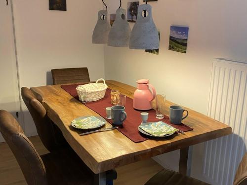 een houten tafel met twee borden en een roze kan bij Ferienwohnung Dick in Schmallenberg