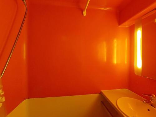La salle de bains est pourvue de murs orange, d'un lavabo et d'un miroir. dans l'établissement Studio cosy pour 2 personnes, proche pistes et commodités, Arc 1800 - FR-1-411-293, à Arc 1800