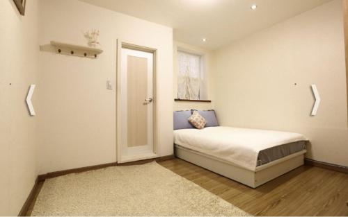 um pequeno quarto com uma cama e uma janela em Yujeong Guesthouse em Jeonju