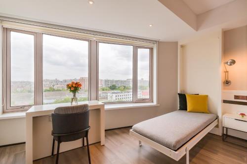 a bedroom with a desk and a bed and windows at Beijing Pudi Hotel in Beijing