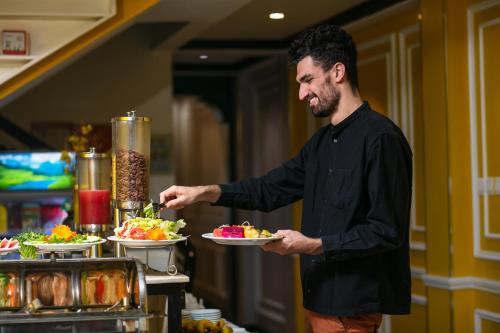 a man is holding a plate of food at Lavender Central Hotel & Spa Hanoi in Hanoi