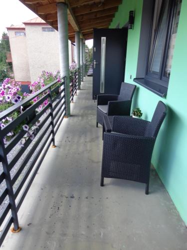 a row of chairs on a porch with flowers at Noclegi-SKAŁKA in Olsztyn