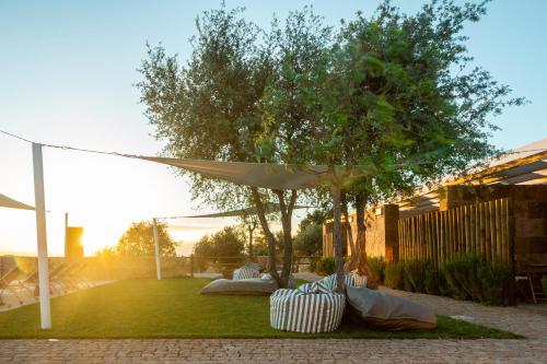 a patio with a white umbrella and chairs on the grass at Reflexos D'Alma Turismo Rural in Estremoz
