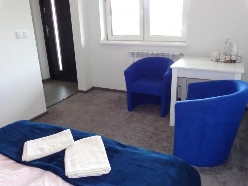 a bedroom with blue chairs and a bed and a desk at Noclegi-SKAŁKA in Olsztyn