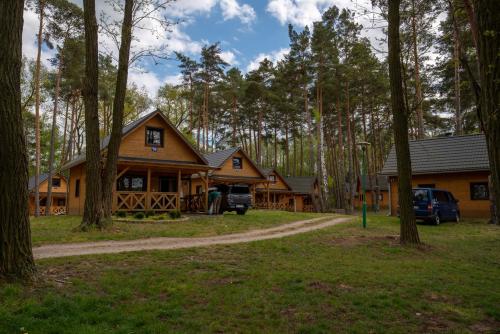 a log cabin in the woods with cars parked in the driveway at Ośrodek Wypoczynkowy Laguna in Lubniewice