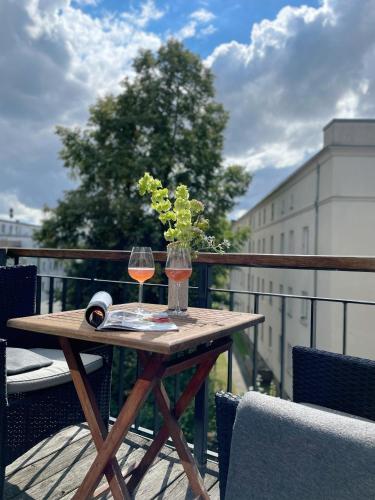 a wooden table with a glass of wine on a balcony at The Green Rostock Apartment Hotel in Rostock