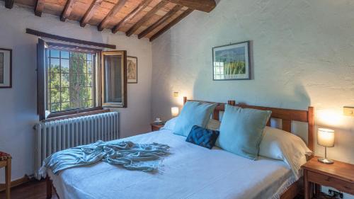 a bedroom with a bed with blue sheets and a window at LE GRAZIE 8, Emma Villas in Montepulciano
