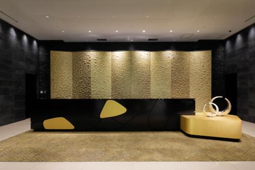a lobby with a yellow table and a gold wall at KOKO HOTEL Premier Kumamoto in Kumamoto