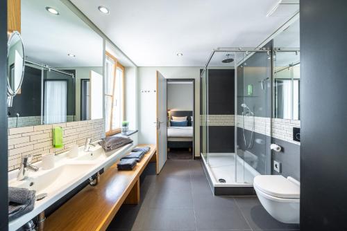 a bathroom with a shower and two sinks and a toilet at The Green Rostock Apartment Hotel in Rostock