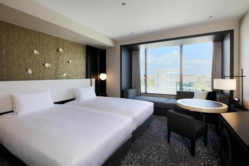 熊本市にあるKOKO HOTEL Premier 熊本のベッド、デスク、窓が備わるホテルルームです。