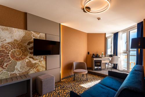 a hotel room with a blue couch and a table at Hotel Helikon, Keszthely in Keszthely