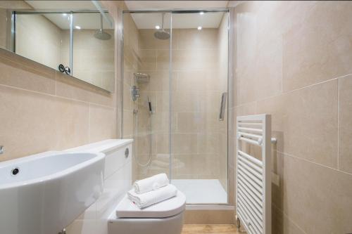 e bagno con doccia, servizi igienici e lavandino. di Mansion House Apartments a Londra