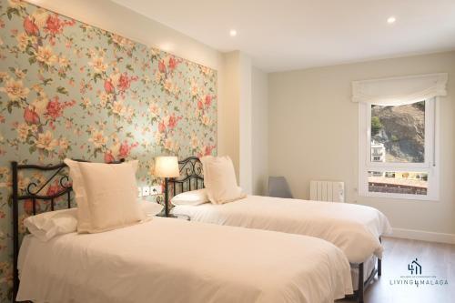 2 Betten in einem Zimmer mit Blumentapete in der Unterkunft Living4Malaga Arenal Superior Beach in Málaga