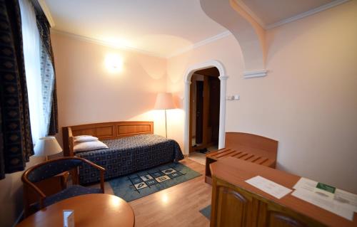 a bedroom with a bed and a desk and a table at Hotel Pannonia in Miskolc