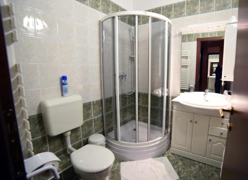 a bathroom with a shower, toilet and sink at Hotel Pannonia in Miskolc