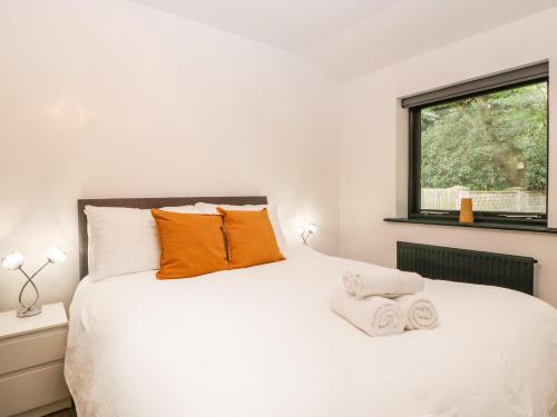 una camera da letto con un grande letto bianco con cuscini arancioni di The Cottage a Wimborne Minster