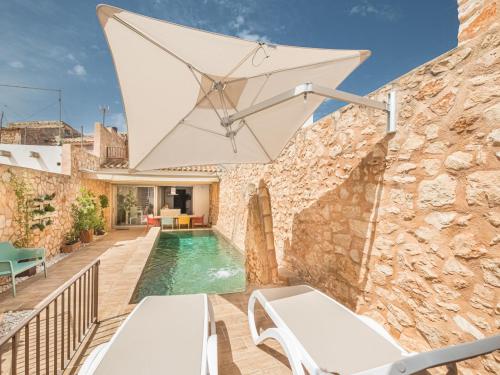 an outdoor patio with a pool and an umbrella at Holiday Home Cordella - SNY101 by Interhome in Santanyi