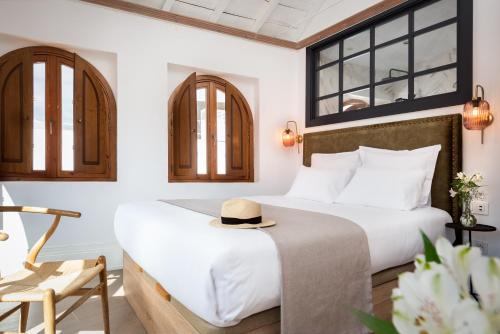 a hotel room with a bed with a hat on it at Casa del Gobernador by Época Suites in Seville